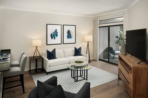 A living room with a white sofa, a coffee table, and a television.