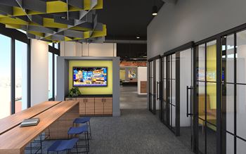 A modern office space with a long wooden table and chairs, a TV screen, and a yellow and black hanging light fixture.