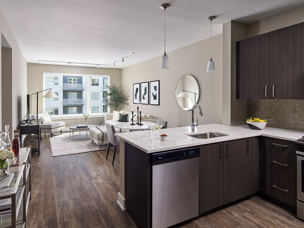 A modern kitchen with dark wood floors and stainless steel appliances.