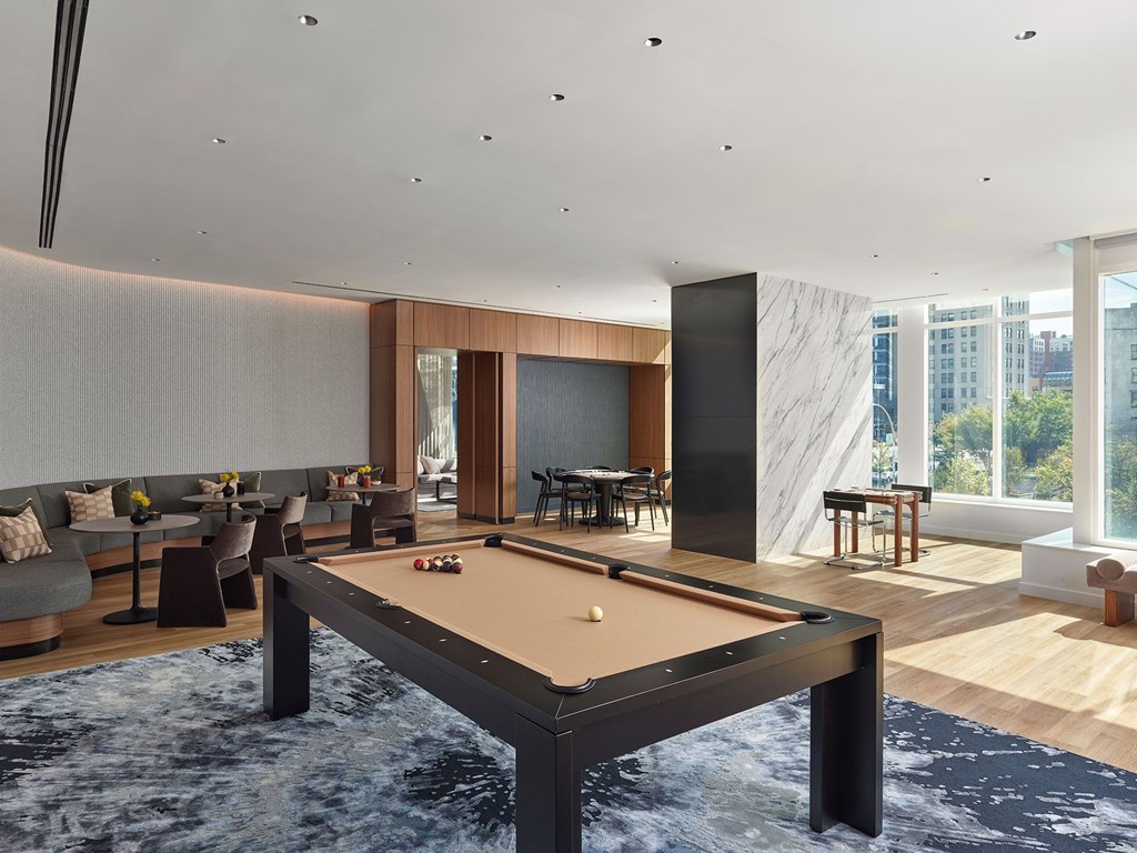 A pool table is in the middle of a room with a couch and a dining table.