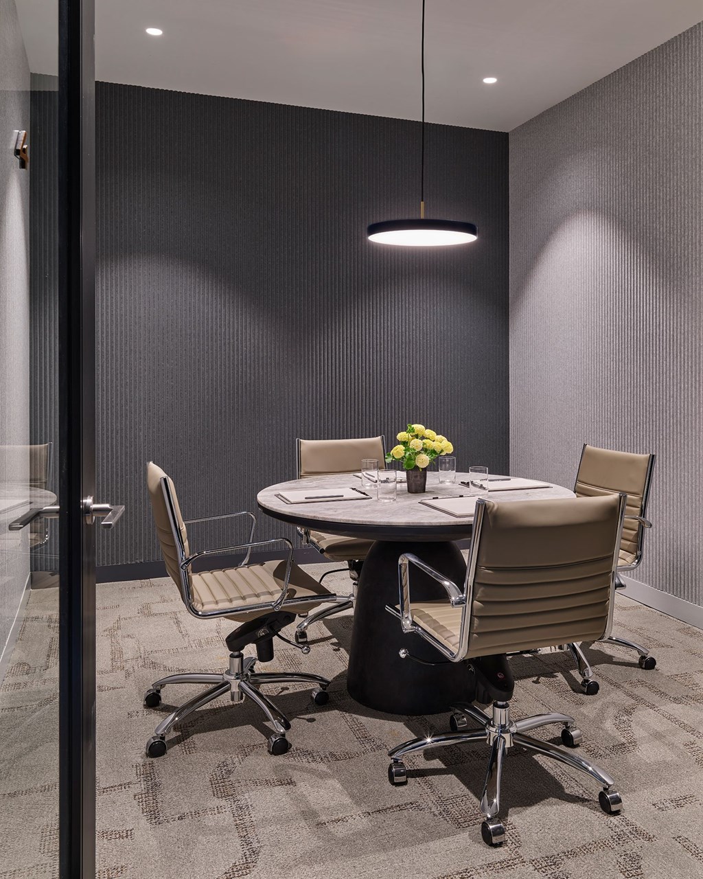 A conference room with a table, chairs, and a flower vase.