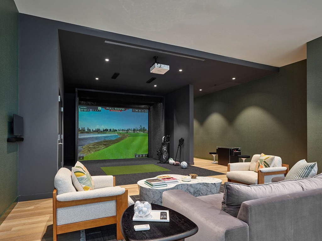 A modern living room with a large screen and comfortable seating.