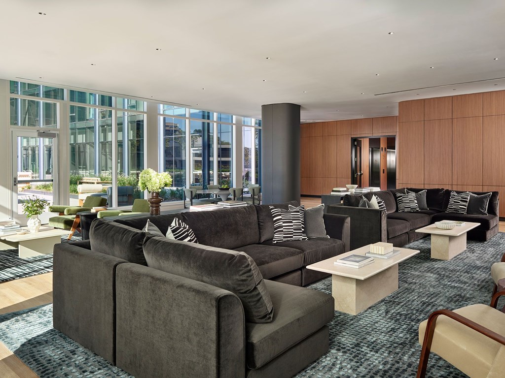 A living room with grey couches and a blue rug.