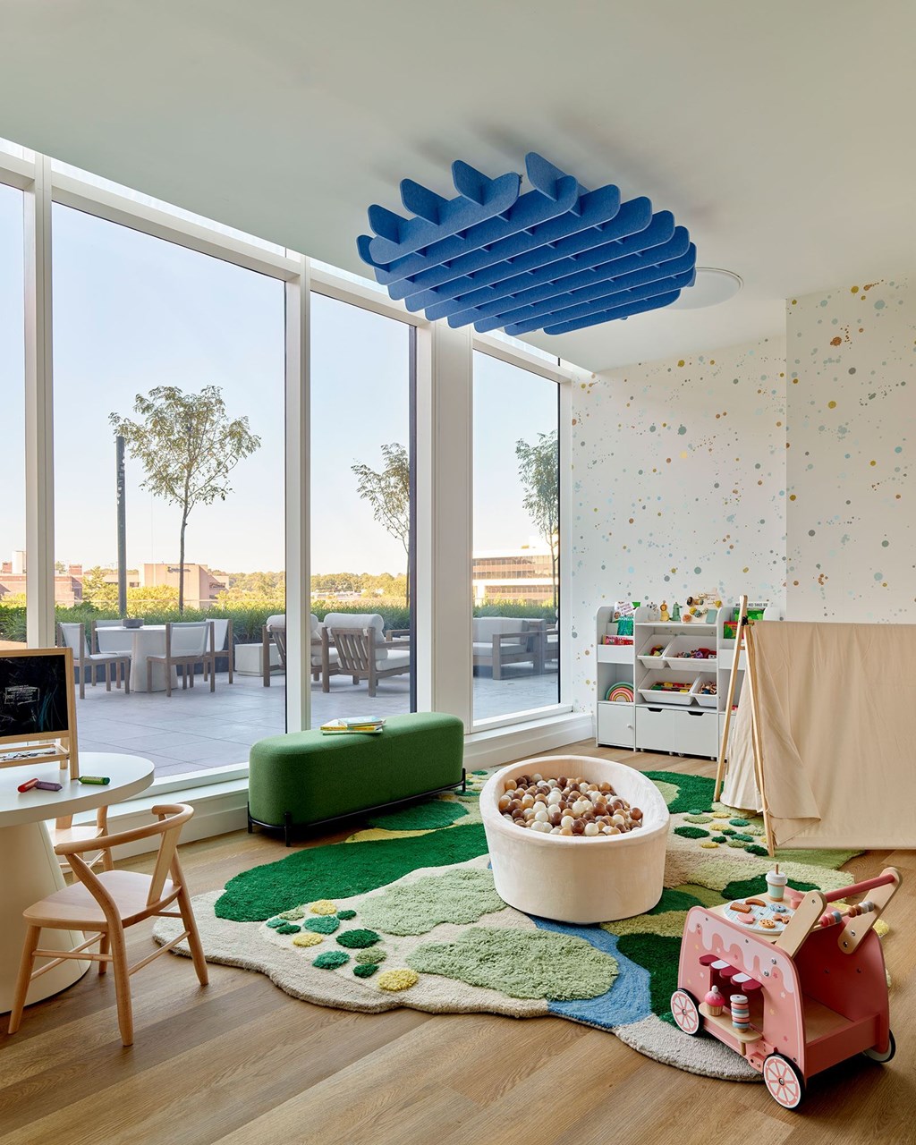 A room with a green rug and a red wagon on the floor.
