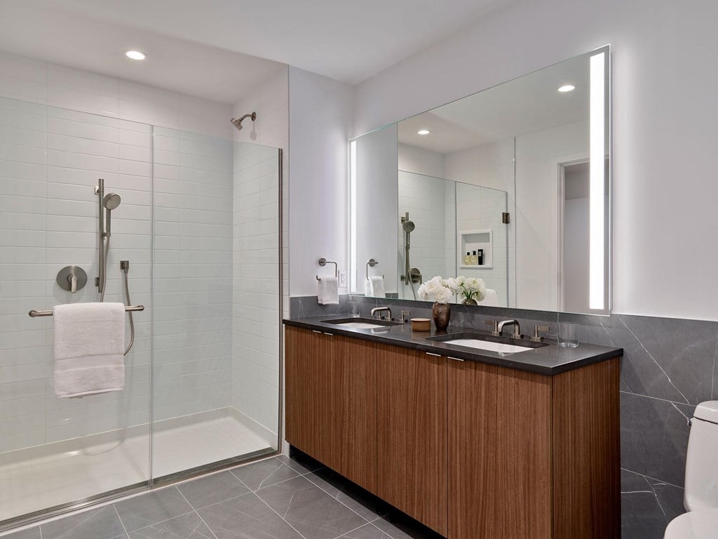 A modern bathroom with a wooden vanity and a glass shower.