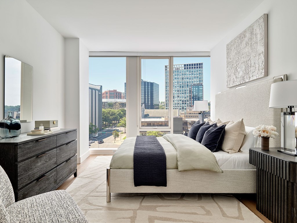 A modern bedroom with a large bed and a view of the city.