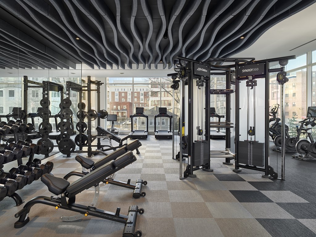 A gym with a variety of equipment including weights and a rowing machine.