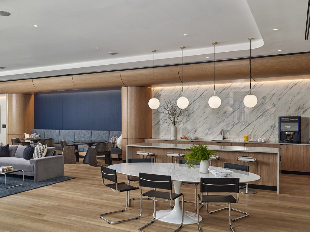 A modern dining area with a marble counter and black chairs.