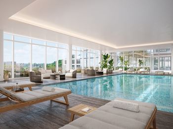 A large indoor swimming pool with lounge chairs and a view of the outdoors.