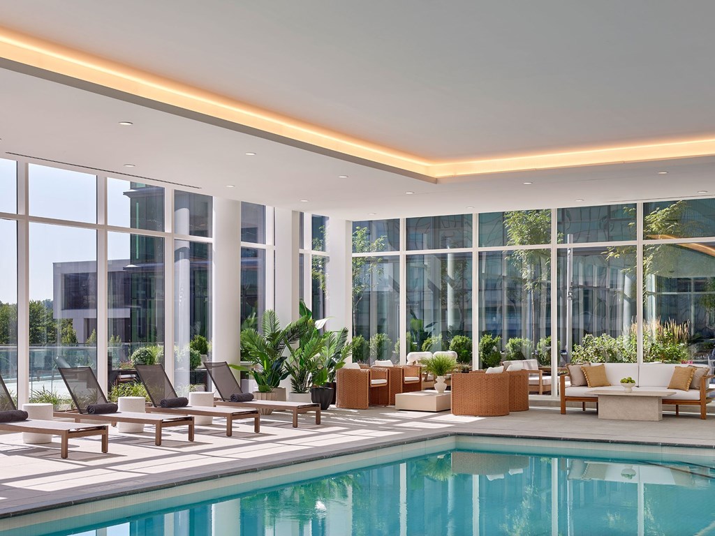 A large indoor swimming pool with lounge chairs and plants.