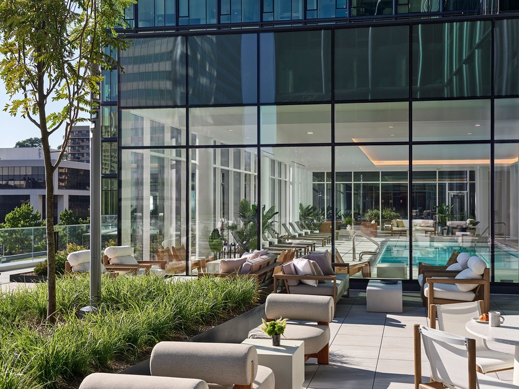 A modern outdoor seating area with white furniture and a glass wall.