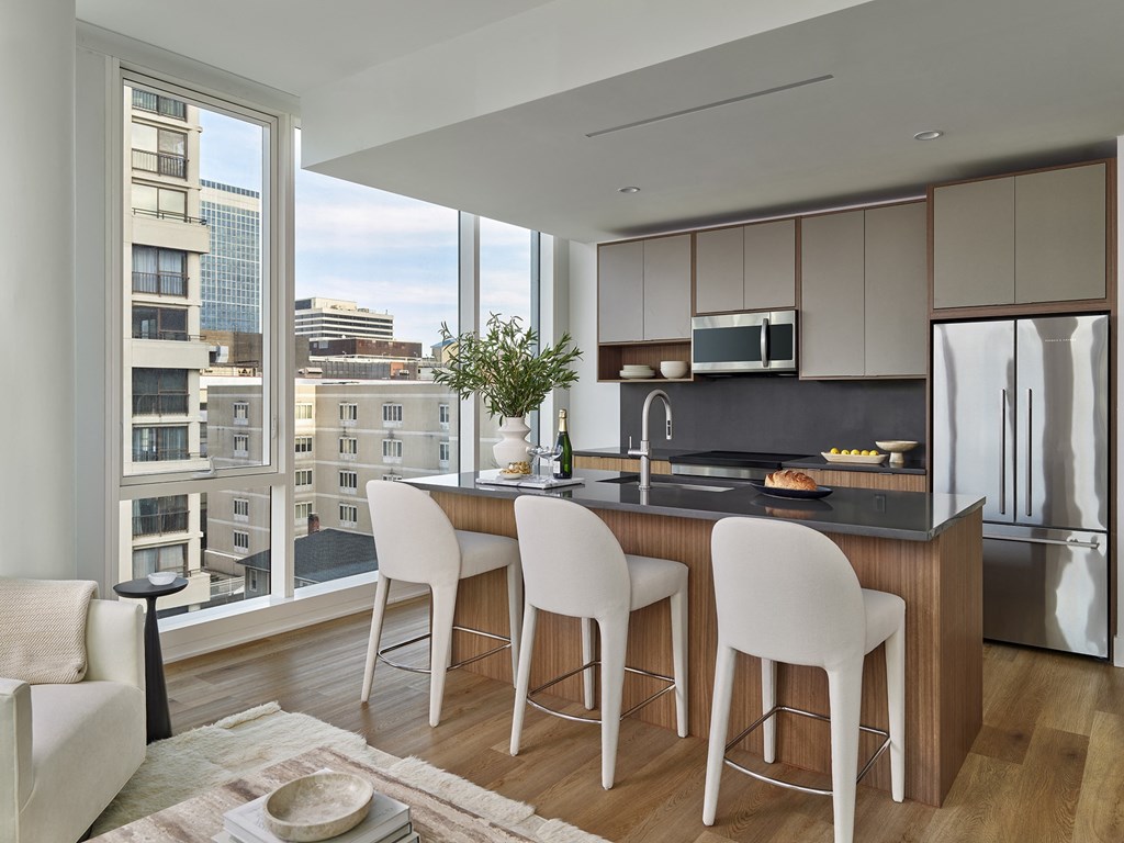 A modern kitchen with white chairs and a view of the city.