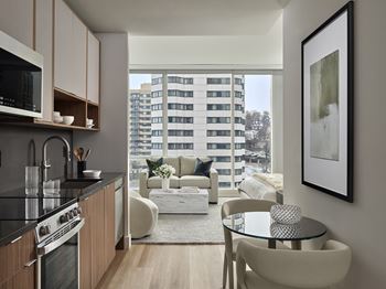 A modern kitchen with a view of a balcony with a white couch and a table.