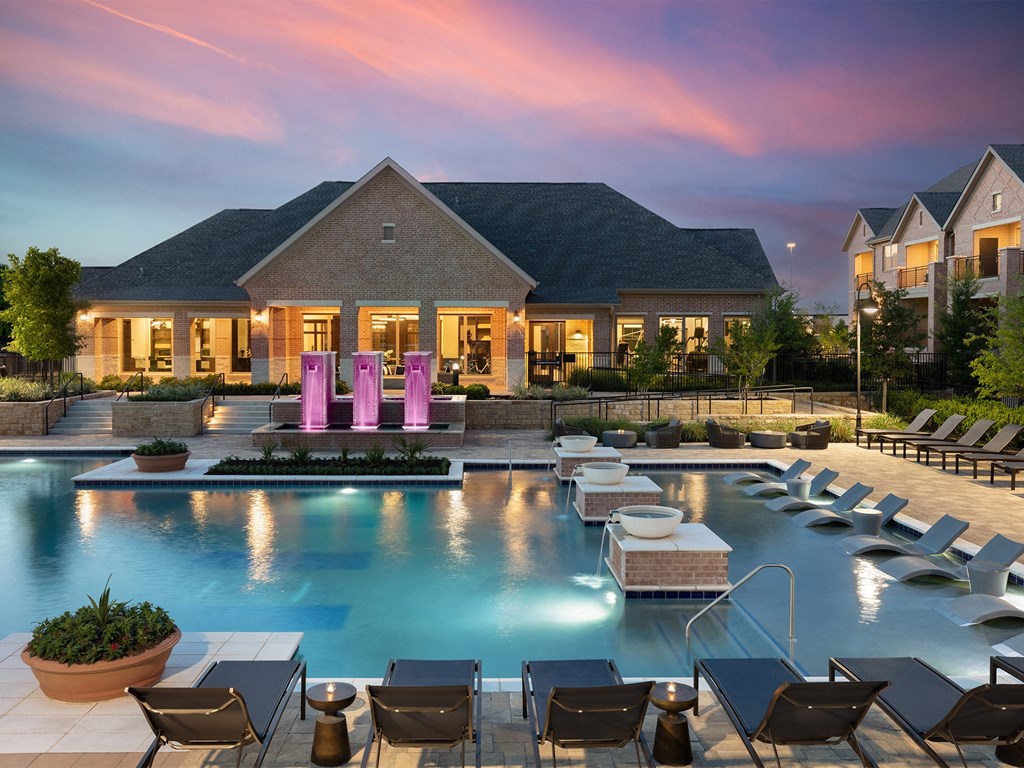 a large swimming pool with lounge chairs and a house in the background