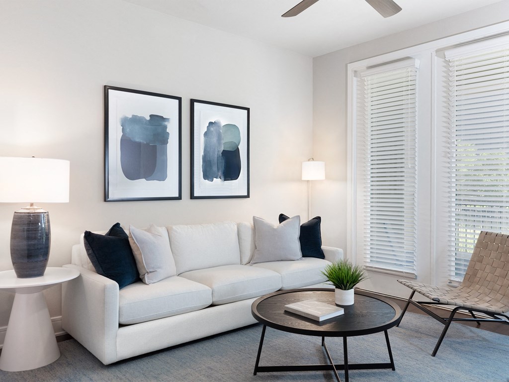 a living room with a white couch and two paintings on the wall