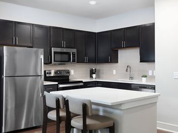 A kitchen with black cabinets and a white island.