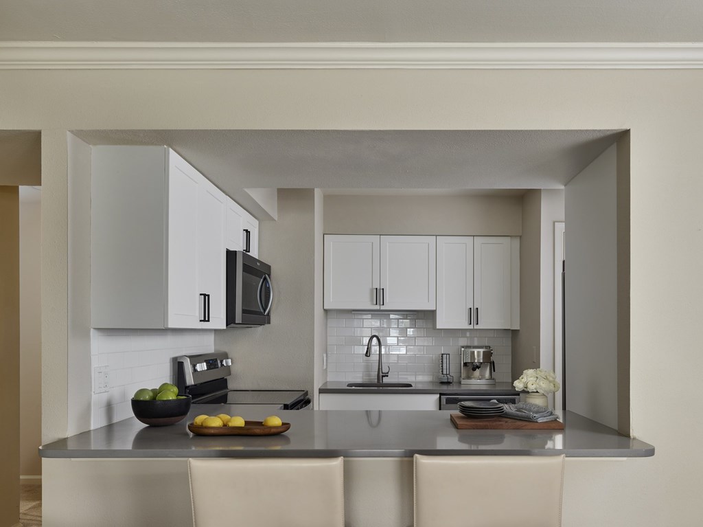 A modern kitchen with a bowl of fruit on the counter.