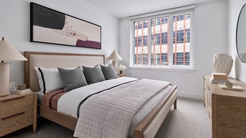 A bedroom with a large bed, two nightstands, and a painting on the wall.