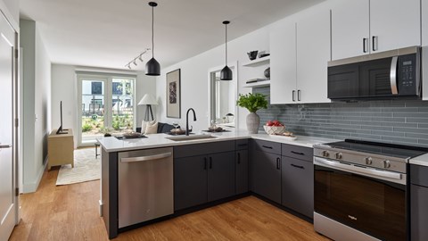 A modern kitchen with dark grey cabinets and stainless steel appliances.