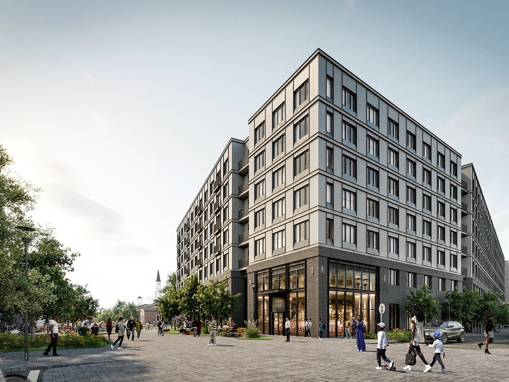 A large, modern building with many windows is surrounded by a plaza with people walking around.