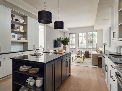 A modern kitchen with a black island and pendant lights.