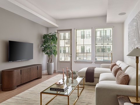 A living room with a glass coffee table and a large flat screen TV mounted on the wall.