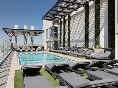 a pool on the rooftop of a building with lounge chairs