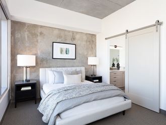 a bedroom with a white bed and a concrete wall