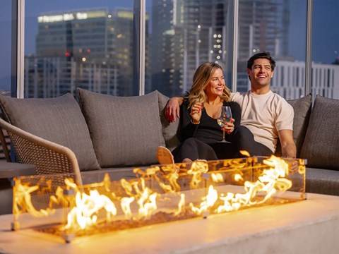 a man and woman sitting on a couch in front of a fire