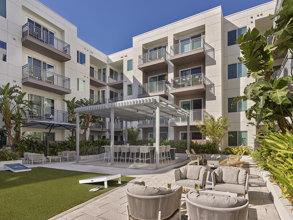 A modern apartment complex with a communal outdoor area featuring a table and chairs.