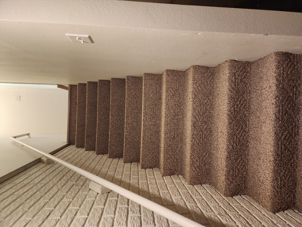 A room with a brown carpeted staircase.