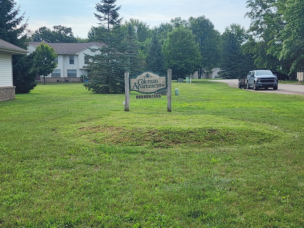 A sign for Glen Arms Apartments stands in a grassy field.