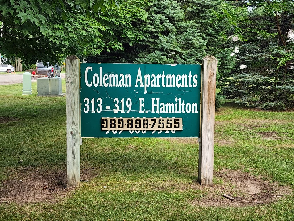 A sign for Coleman Apartments with a phone number on it.