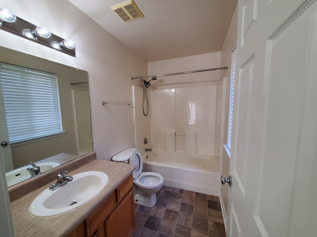 A bathroom with a sink, mirror, toilet, and bathtub.