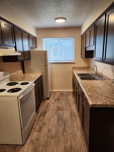 A kitchen with a white stove and dark brown cabinets.