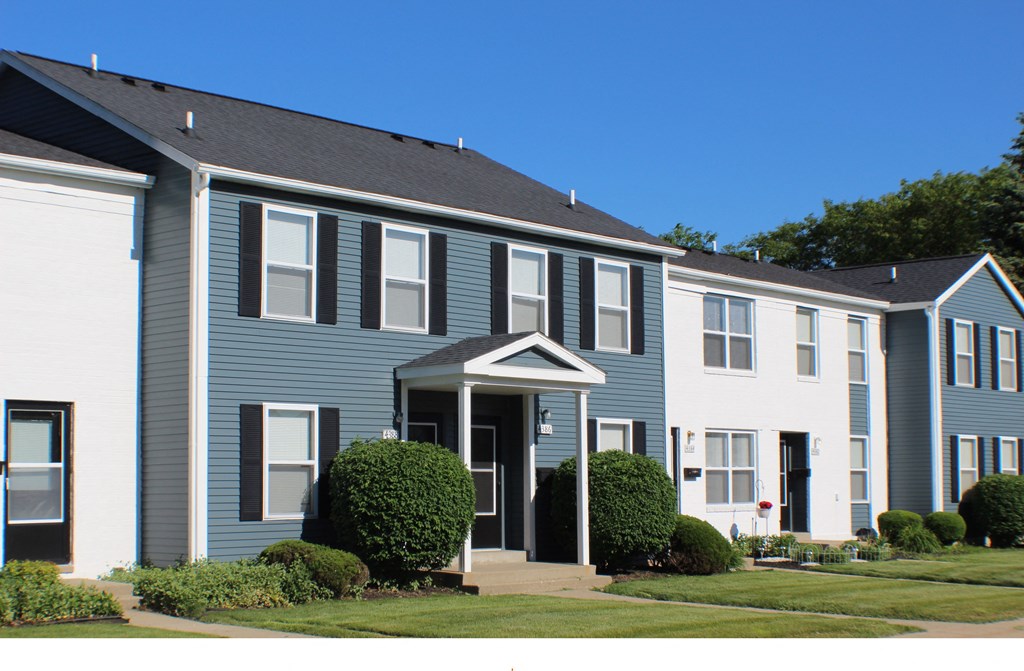 a blue and white apartment building with a grassy yard