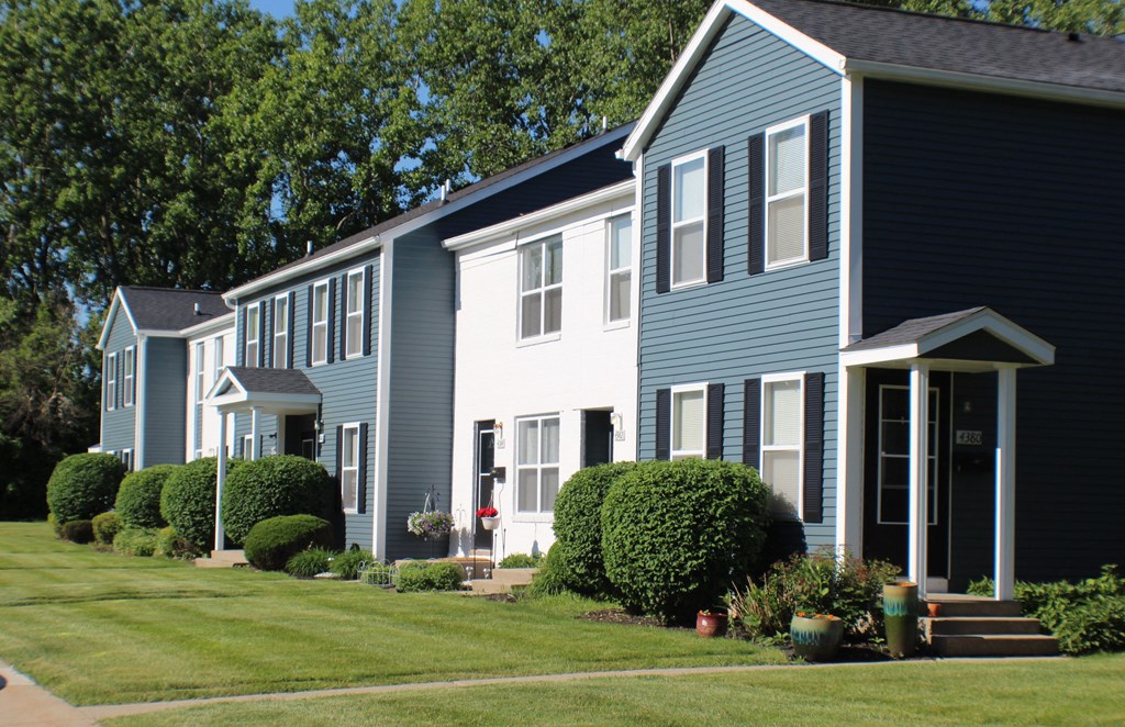a row of houses with blue and white siding and a lawn