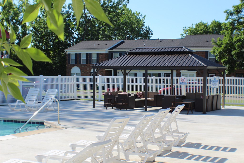 a pool with chairs and a gazebo in front of a house