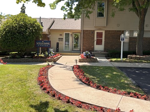 a sidewalk in front of a building with flowers and plants