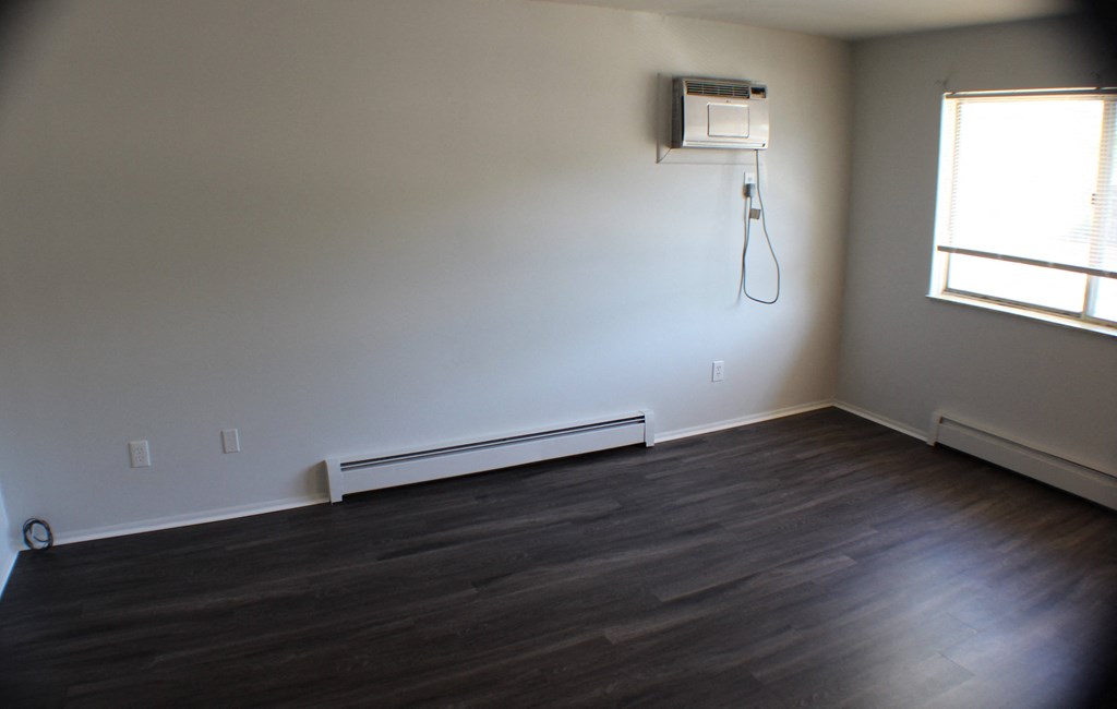 an empty living room with wood floors and a dryer on the wall