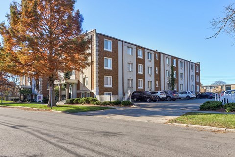 Apartment building with a parking lot in front.