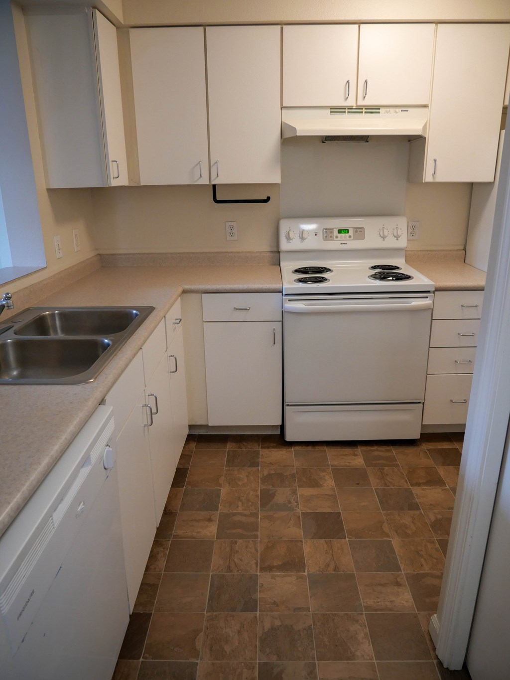 A kitchen with a stove, sink, and cabinets.