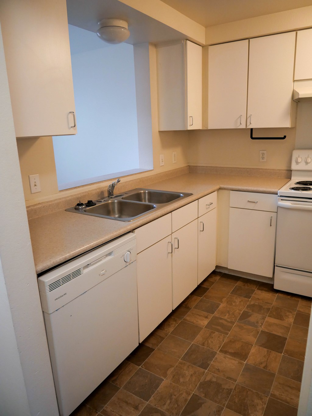 A kitchen with white cabinets and brown tiles.