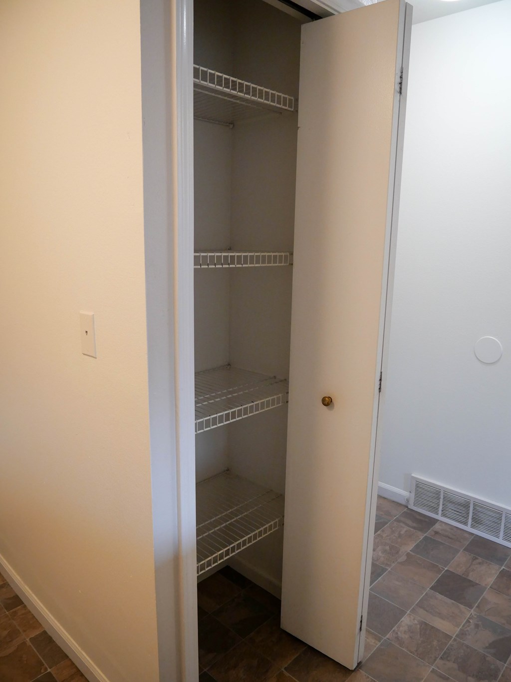 A white door is open to reveal a pantry with empty shelves.