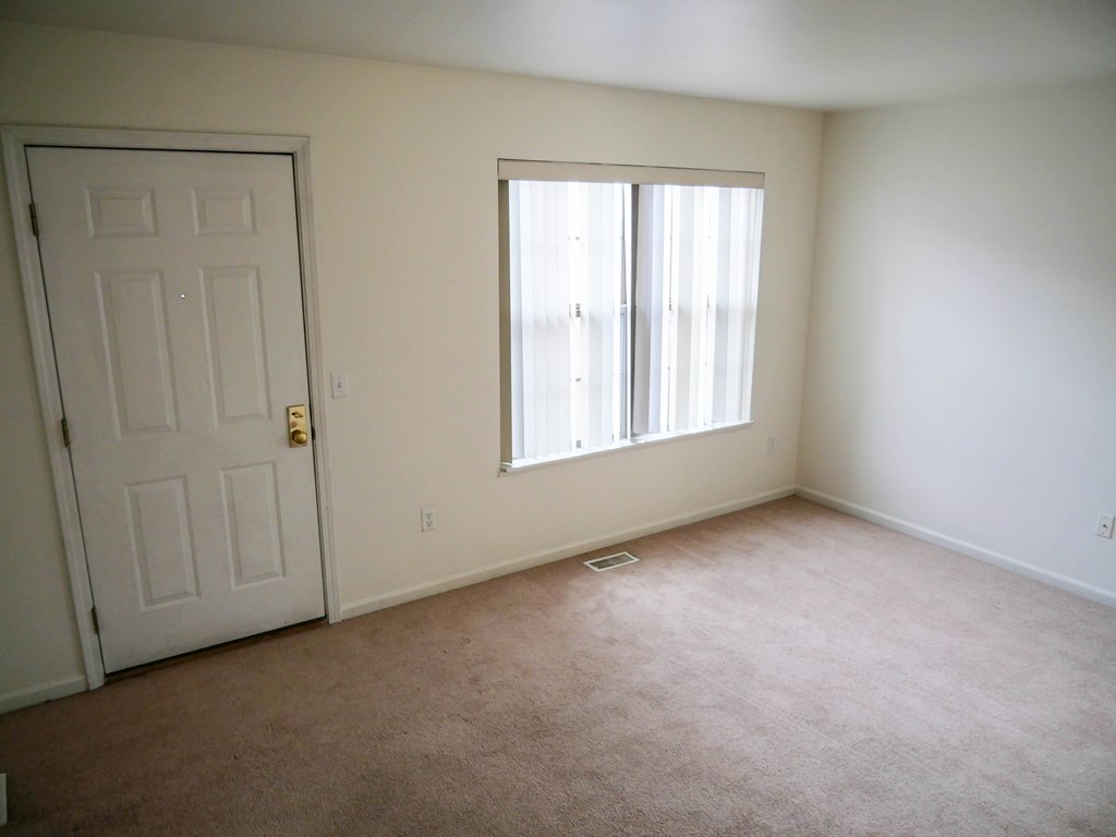 A room with a white door and a window with white blinds.