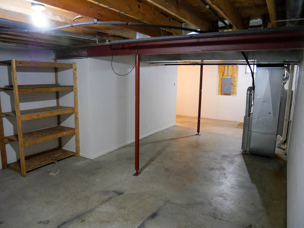 A room with a white wall and a wooden shelf.
