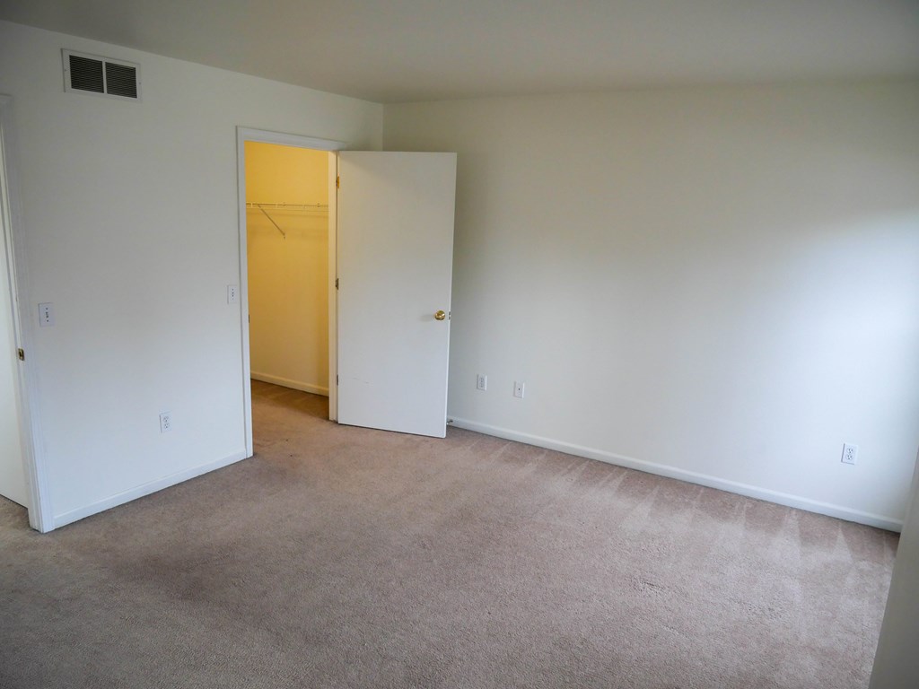 A room with a carpeted floor and a doorway leading to another room.