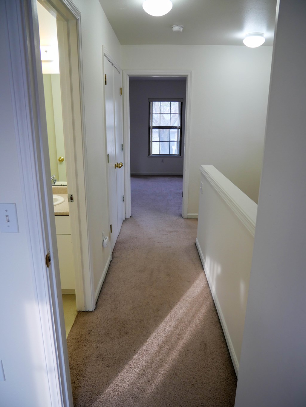 A hallway with a carpeted floor and white walls.