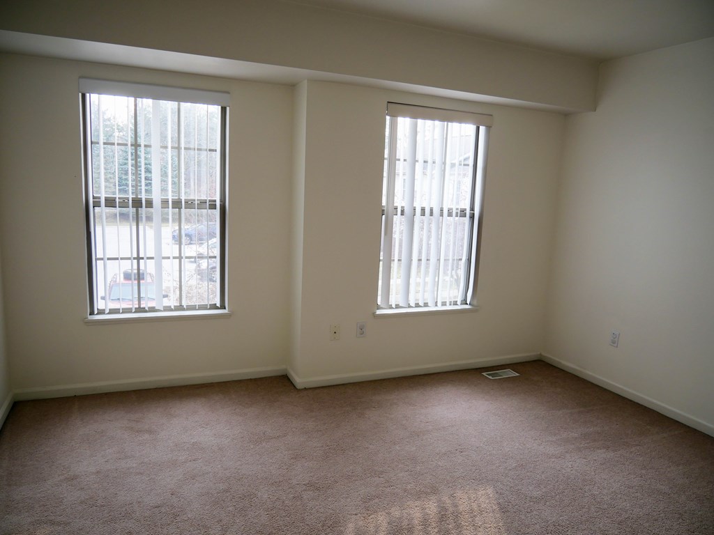 A room with two windows and carpeted flooring.