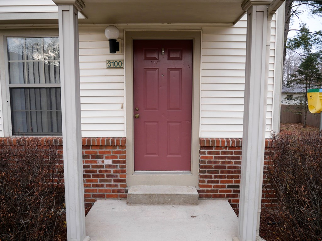A red door with a number 3100 on the wall above it.